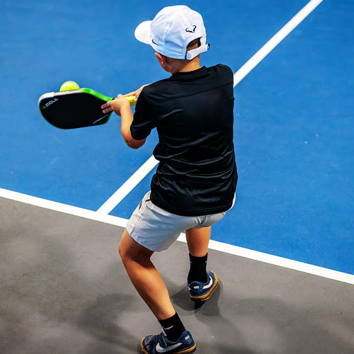 Young pickleball player hitting a forehand shot on an indoor court at The Fort in Fort Lauderdale.