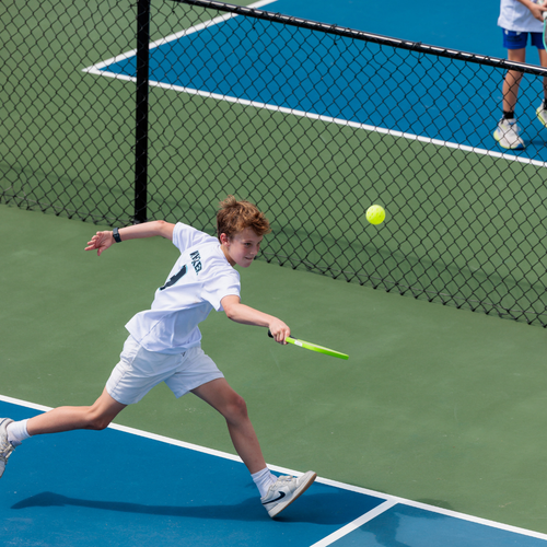 Young pickleball player reaching for a shot during a match on the outdoor courts at The Fort in Fort Lauderdale.