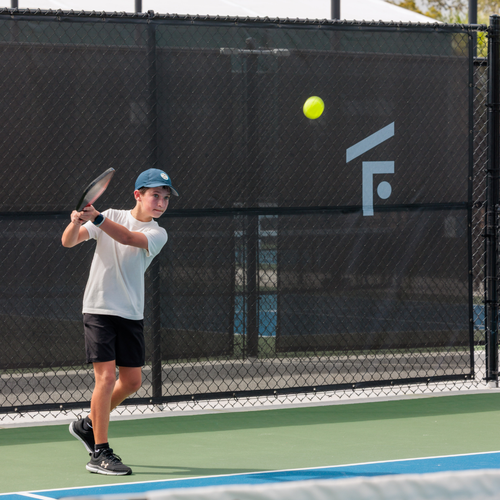 Young pickleball player practicing a forehand shot on the outdoor courts at The Fort in Fort Lauderdale.