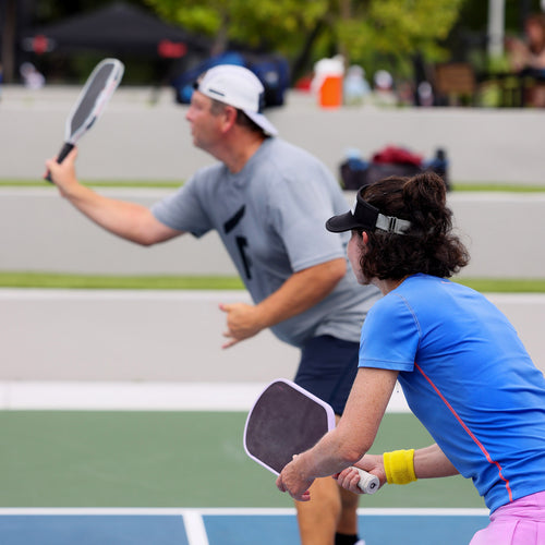 Two players competing in a pickleball doubles match on an outdoor court
