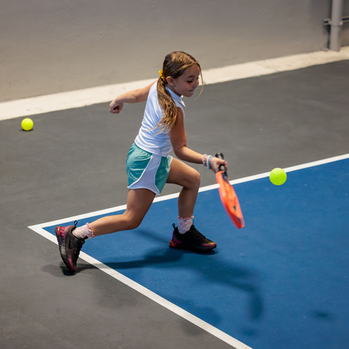 Young pickleball player running for a shot during a training session at The Fort indoor courts.